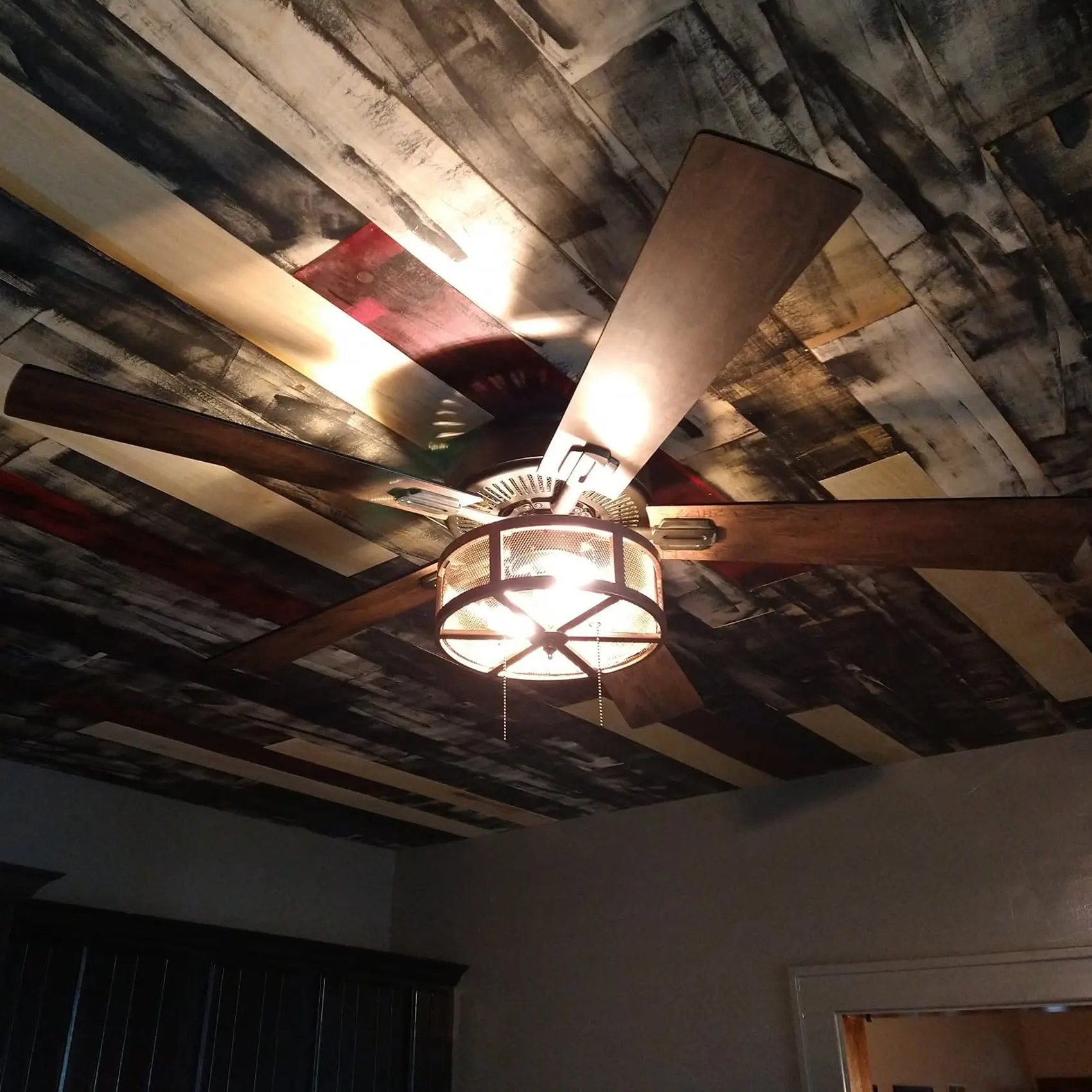 A custom reclaimed-wood ceiling with a newly installed ceiling fan